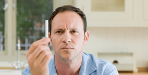 man looking at last cigarette as he attempts to stop smoking