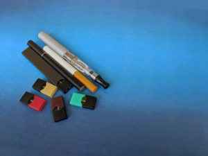 e-cigarette devices on blue background arranged to show examples of tobacco use