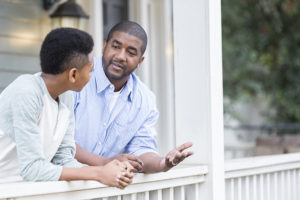 Man standing on porch with his son as he explains e-cigarette risks