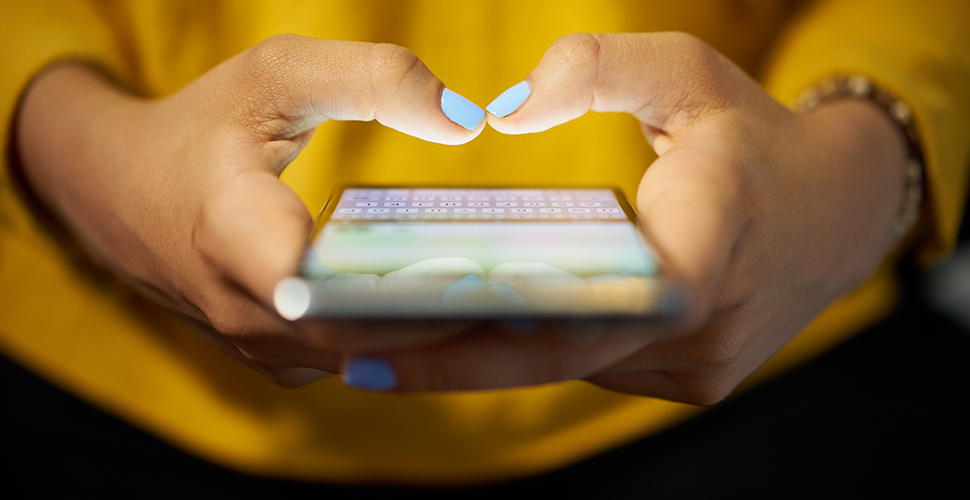 woman in yellow investigating the role of digital tobacco cessation programs integrated into lung cancer screening on her mobile device