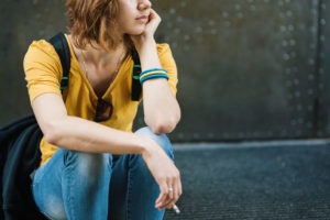 woman in yellow shirt with cigarette waiting to start a tobacco cessation program