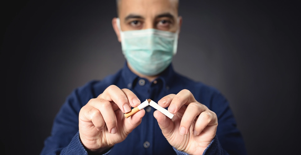 Man With Protective Face Mask Breaking Cigarette After COVID-19, tobacco use surcharges concept