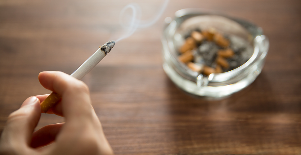 hand of a nicotine dependent person holding a burning cigarette