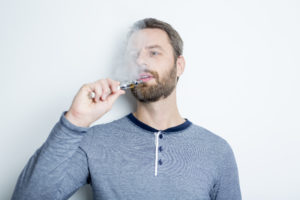 casually dressed man vaping at work