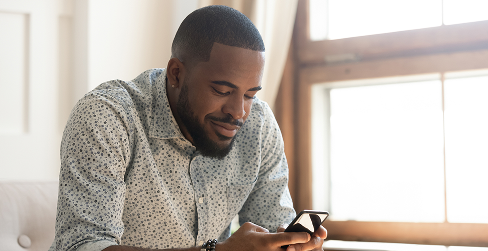 young african american man holding smartphone text messaging as an effective quit smoking method