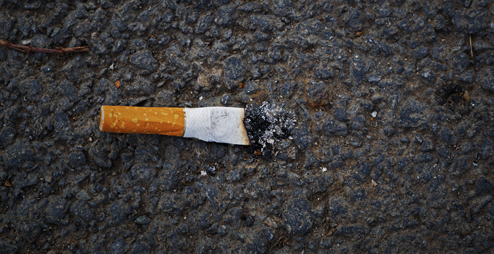 cigarette on the pavement, illustrating the environmental impact of smoking