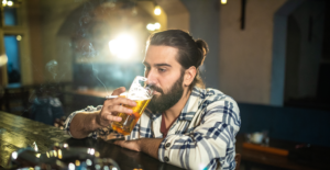Man sitting at bar experiences the interplay of smoking and alcohol.