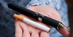 hand holding a cigarette and vape pen to illustrate the duel use of those who smoke and vape
